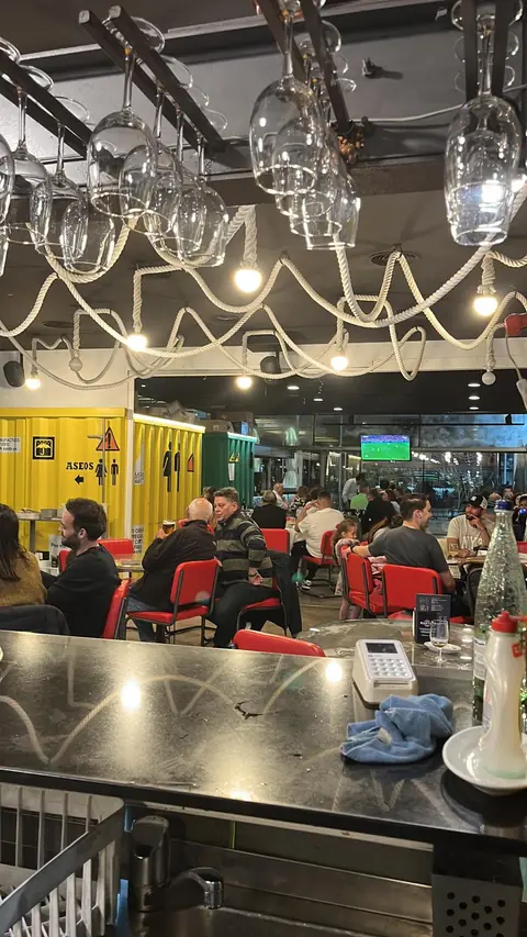 Salón lleno de clientes junto a los contenedores amarillos